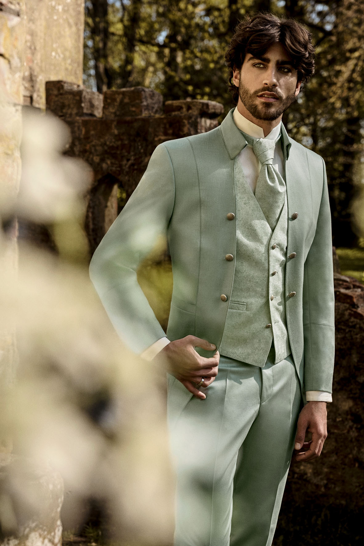 Eleganter Herrenanzug in Mintgrün von Tziacco, getragen im Outdoor-Setting vor historischen Mauern – exklusiver Hochzeitsanzug erhältlich bei Stesa Herrenausstatter Lörrach