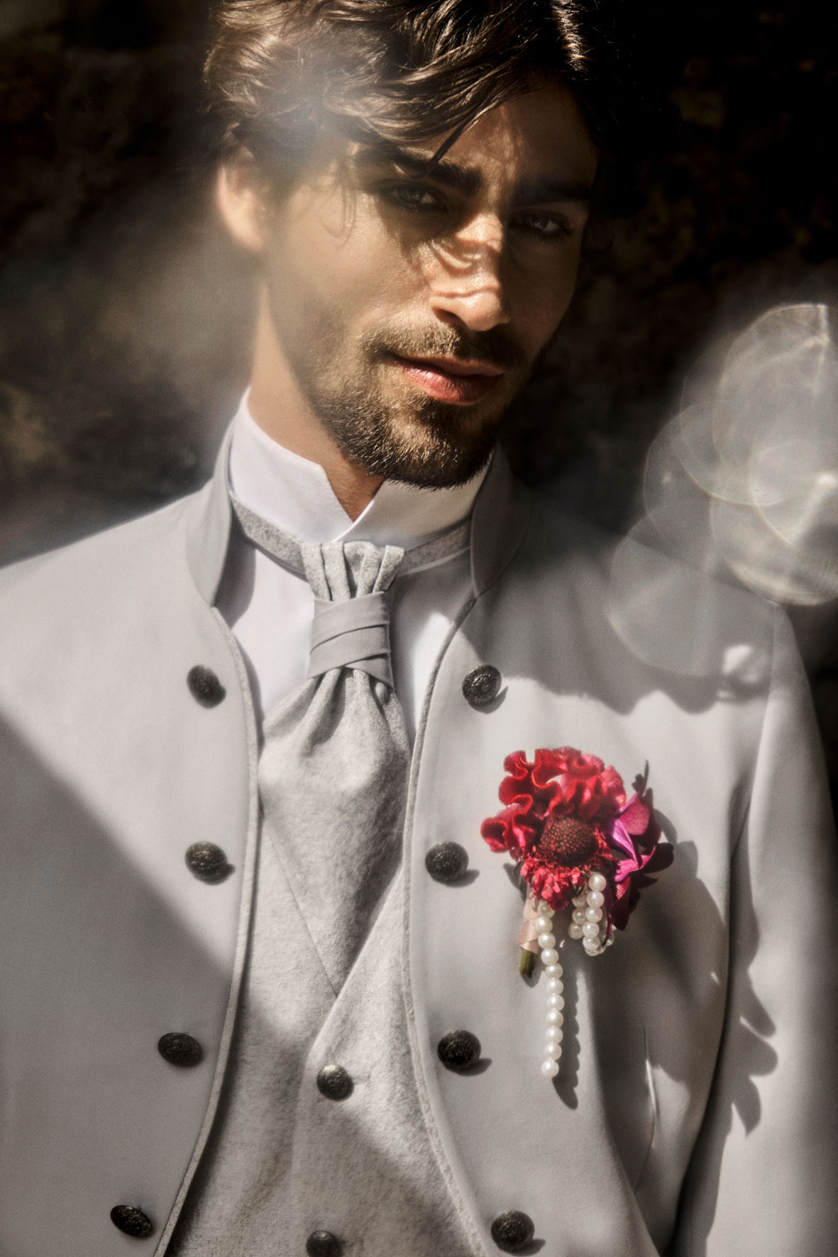 Ausdrucksstark & extravagant – Der TZIACCO-Anzug für den stilvollen Bräutigam räutigam in hellem TZIACCO-Anzug mit Stehkragen, Plastron-Krawatte und roter Ansteckblume mit Perlen – extravaganter Hochzeitsanzug für besondere Anlässe